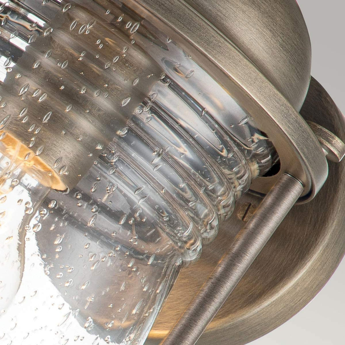 A close-up of the top rim and seeded glass of a bronze outdoor lantern.