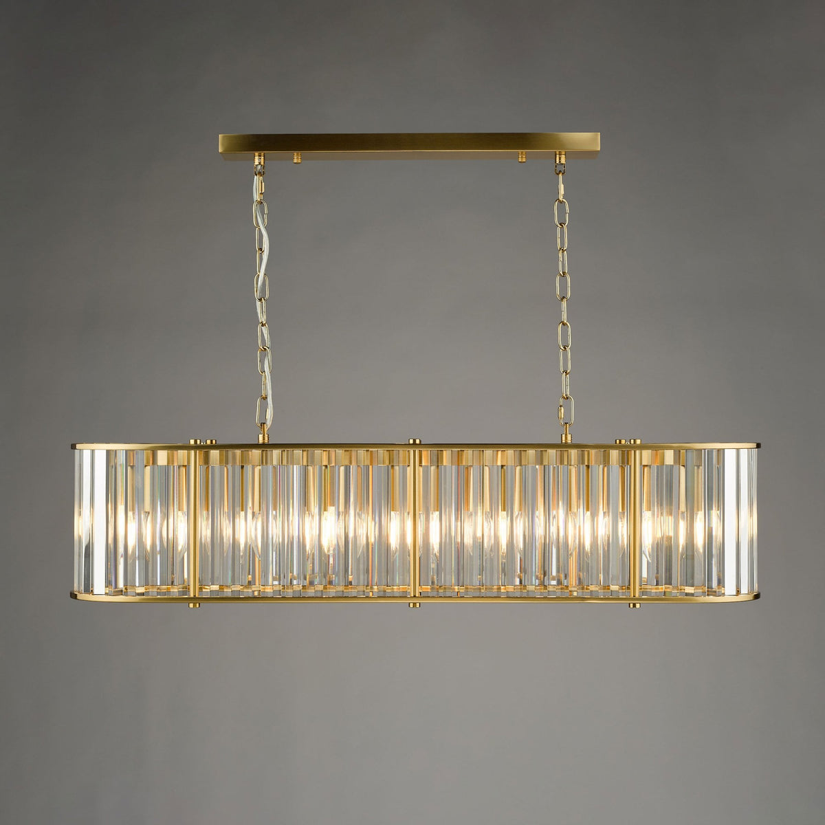 Rectangular brass chandelier with vertical fluted glass panels, emitting a warm glow.