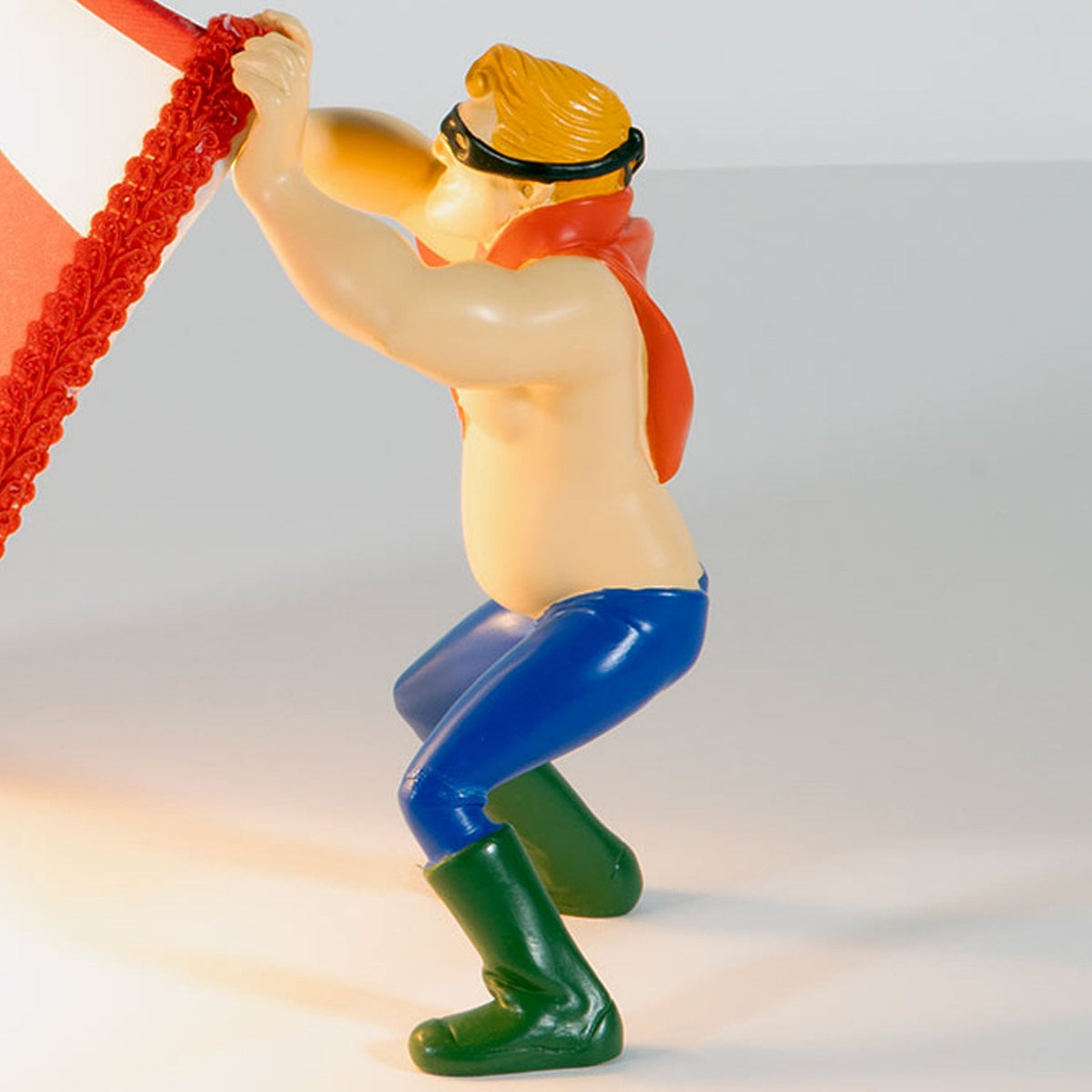 Close-up of a figurine holding up a red and white striped lampshade, creating a light feature.