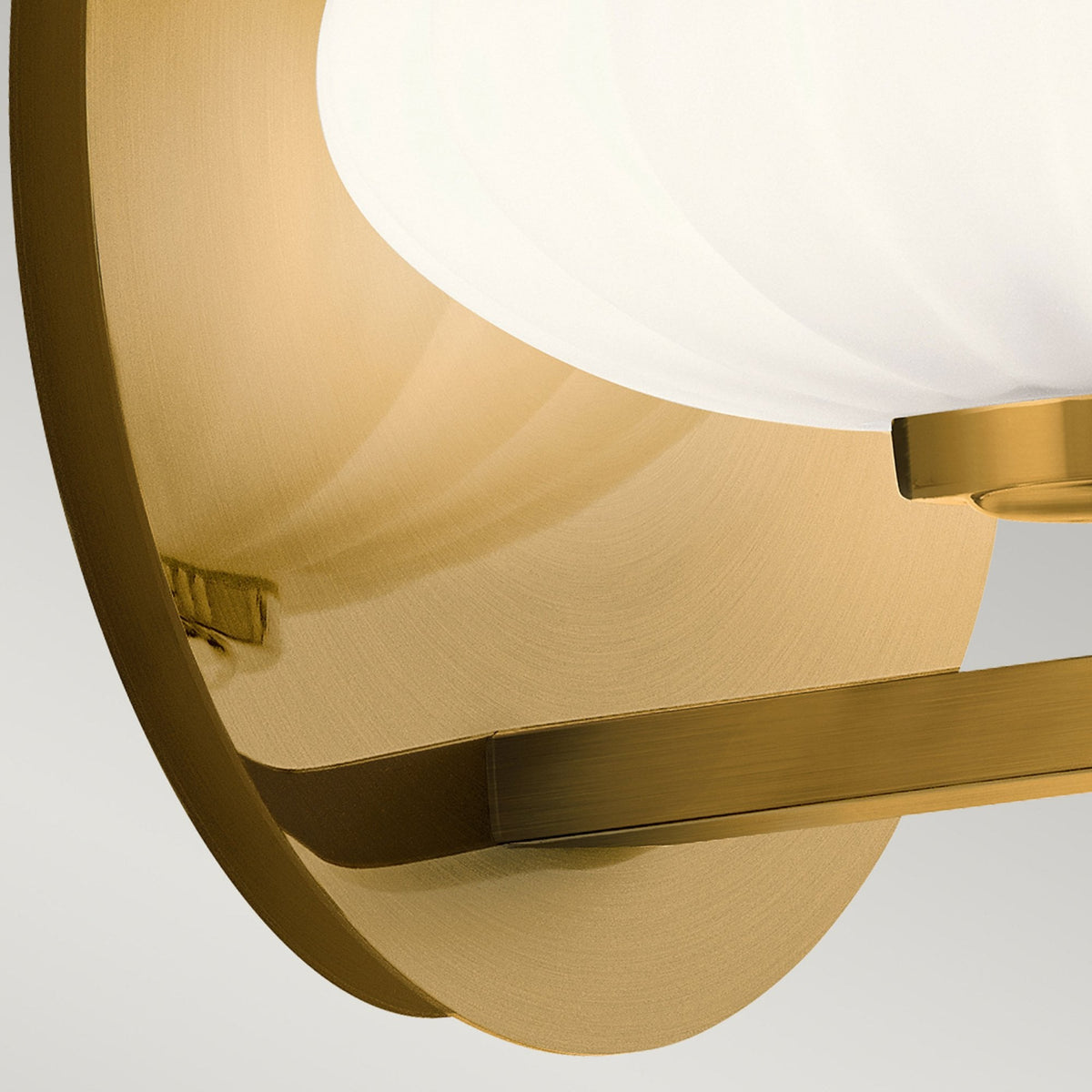 Close-up of the brass backplate and mounting arm of the modern wall light.