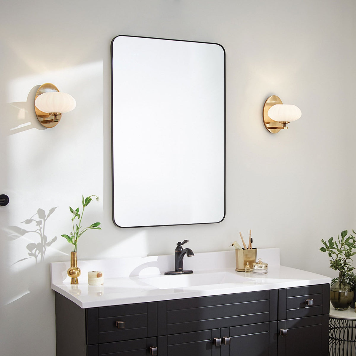A pair of decorative sconces illuminate a sleek bathroom with a large mirror.
