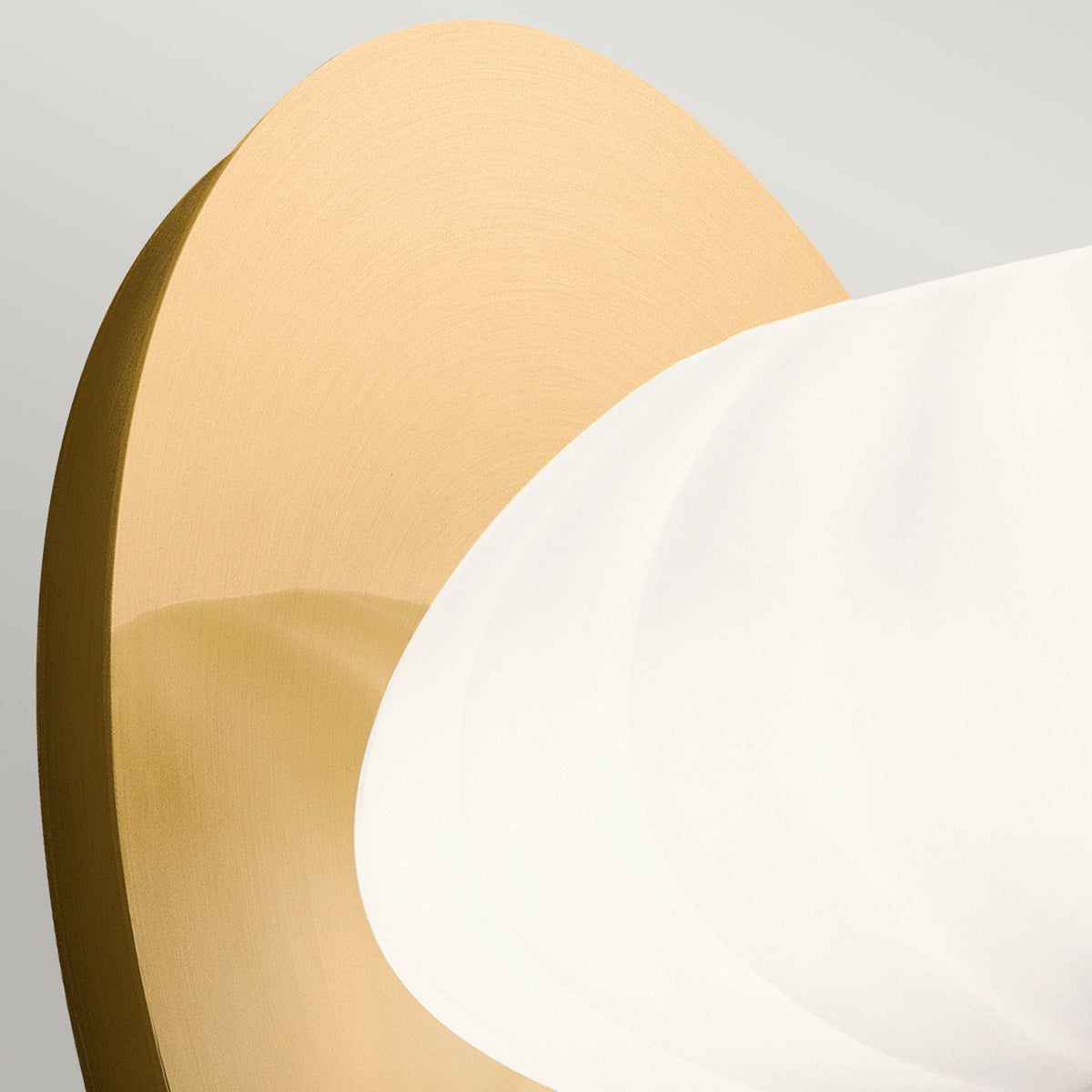 Close-up of the textured white glass shade and smooth brass backplate.