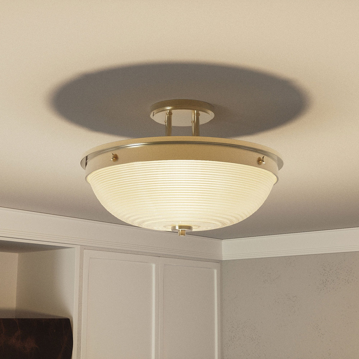 A semi-flush ceiling light with an antique brass finish illuminates a light-coloured room.