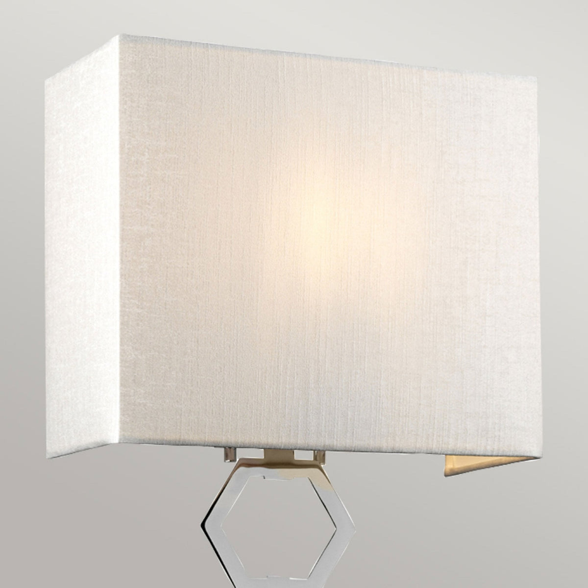 Close-up of the illuminated white fabric rectangular shade of a wall light.