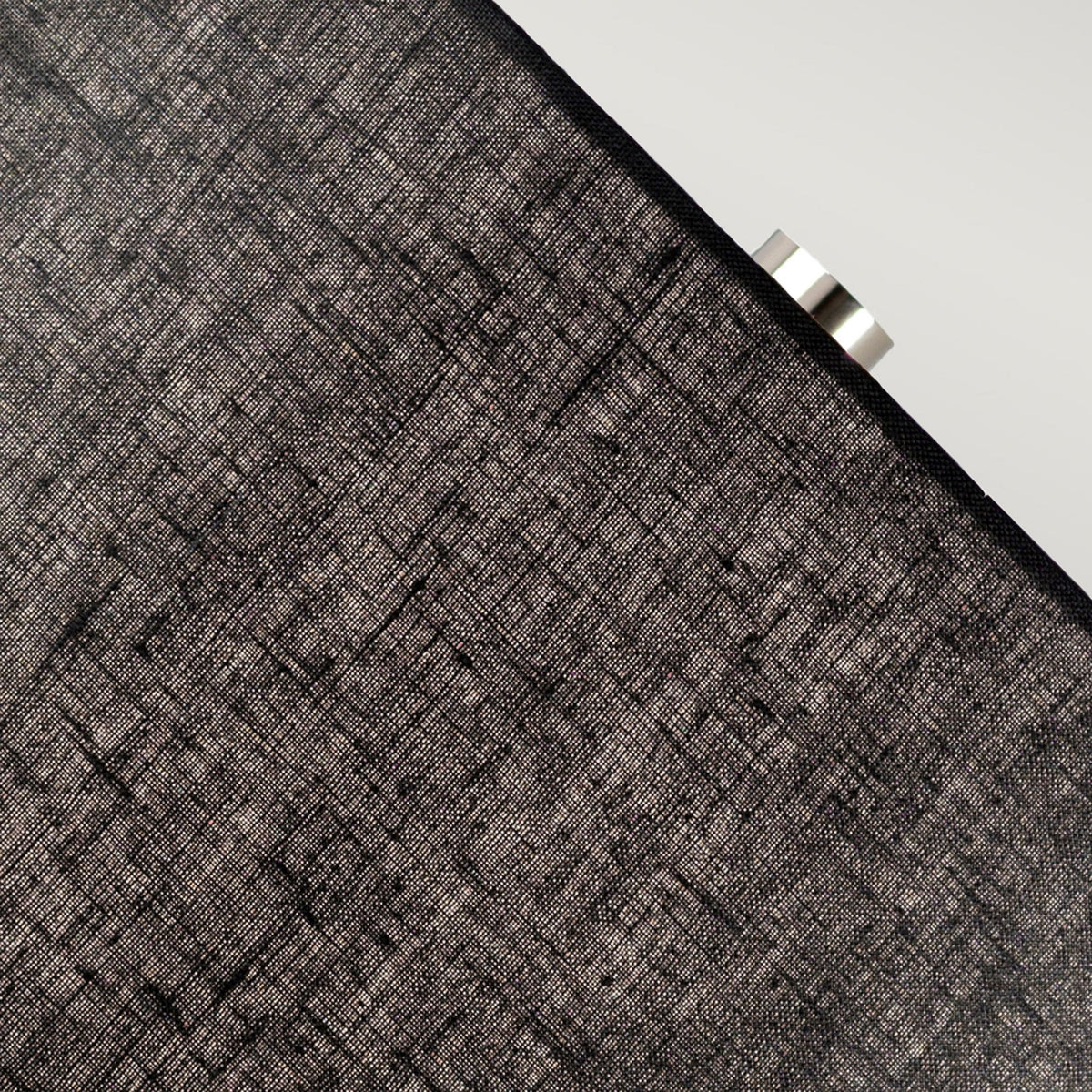 Close up of the textured dark grey lampshade of a table lamp.