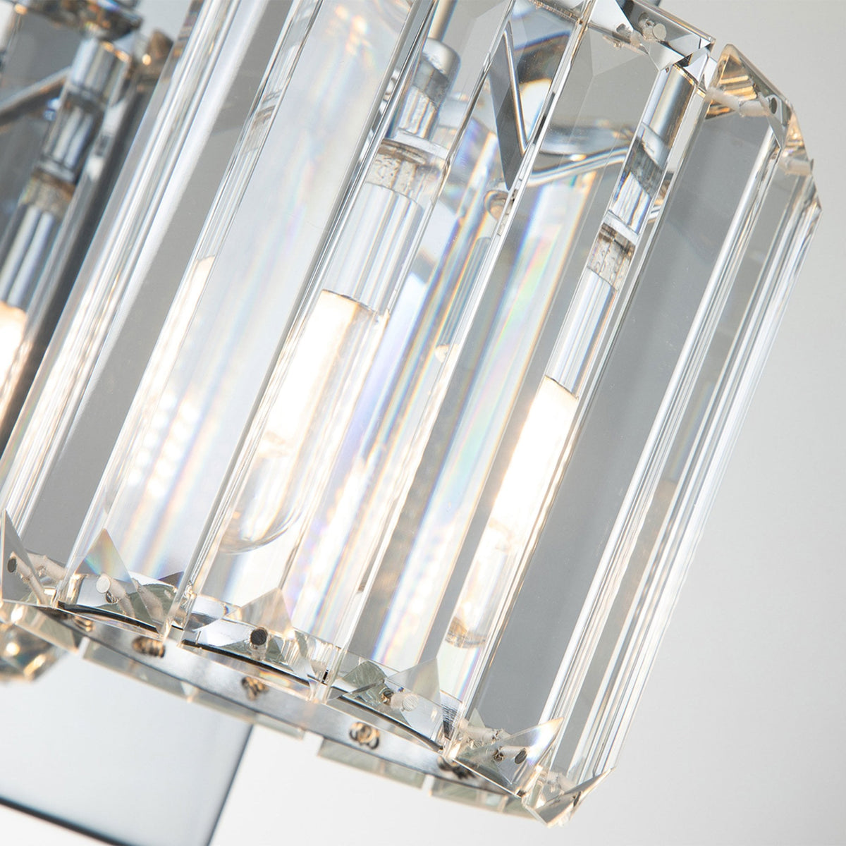 A close-up of the crystal shades on a chrome wall light, showing light through them.