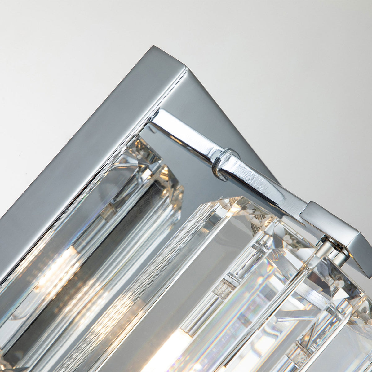 A close-up of the polished chrome backplate and arm of a modern wall light.