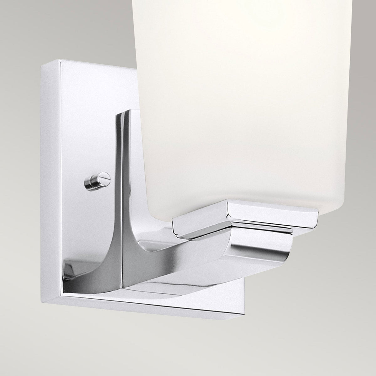 Close-up of the base of a modern chrome wall light with a frosted glass shade.