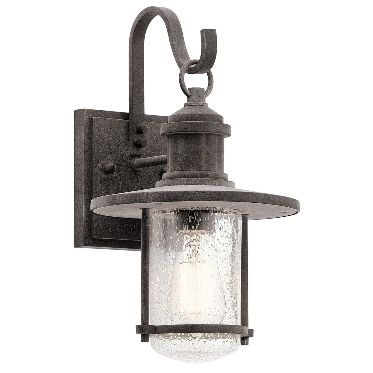 A close-up of a black outdoor wall light with a seeded glass shade and an exposed bulb.