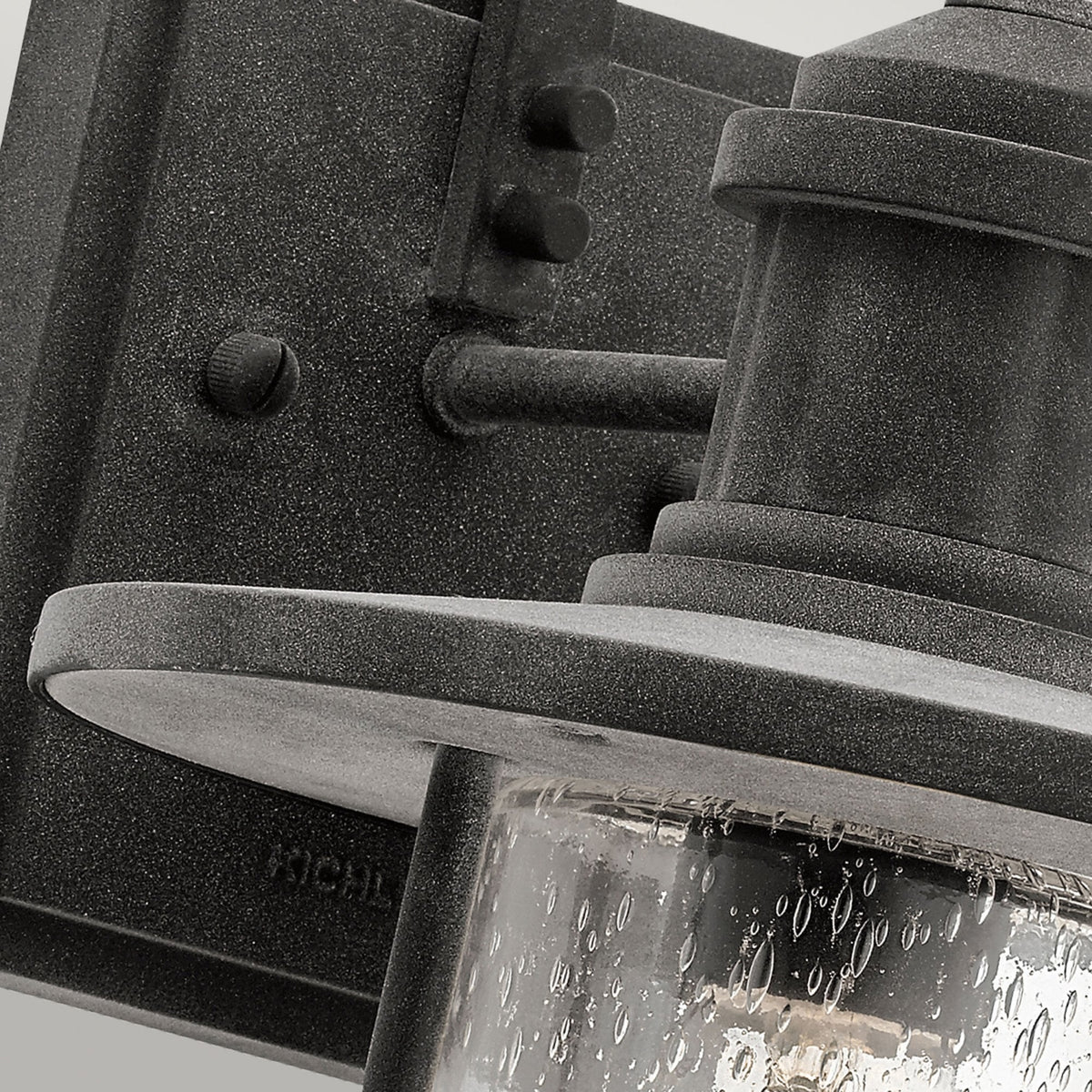 A close-up of the base of the outdoor wall light, showing the seeded glass and textured finish.