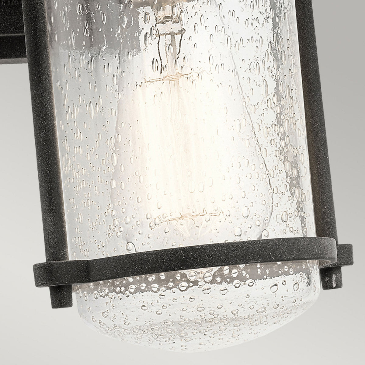 A close-up of the seeded glass shade of the outdoor wall light, with the bulb visible.
