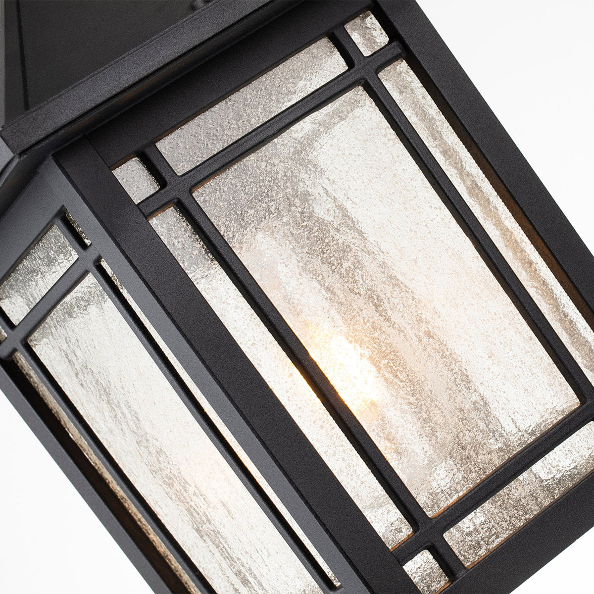 A close-up of the clear seeded glass panels and metal frame of the pendant light.
