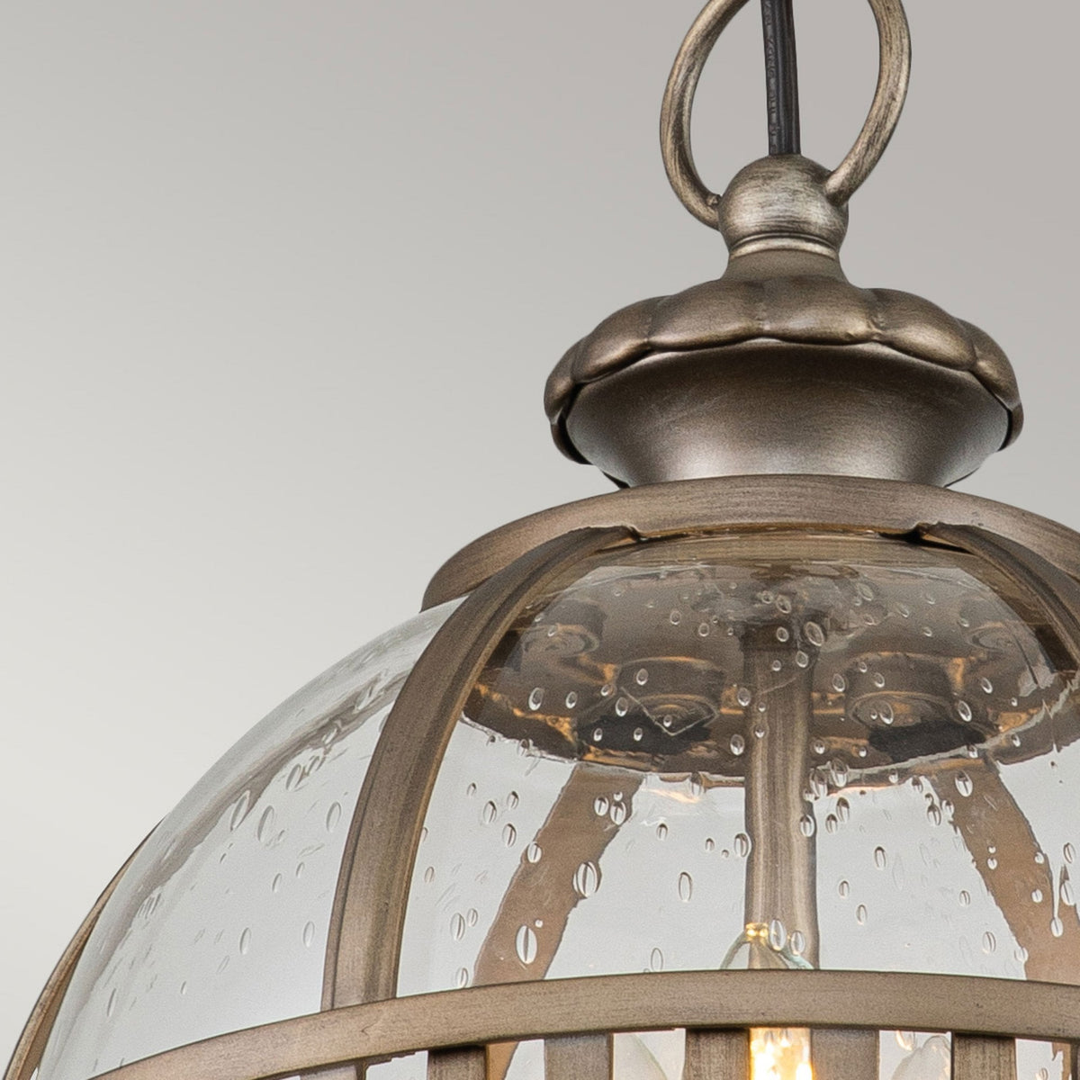 Close-up of the top detail and seeded glass of the bronze outdoor pendant light.