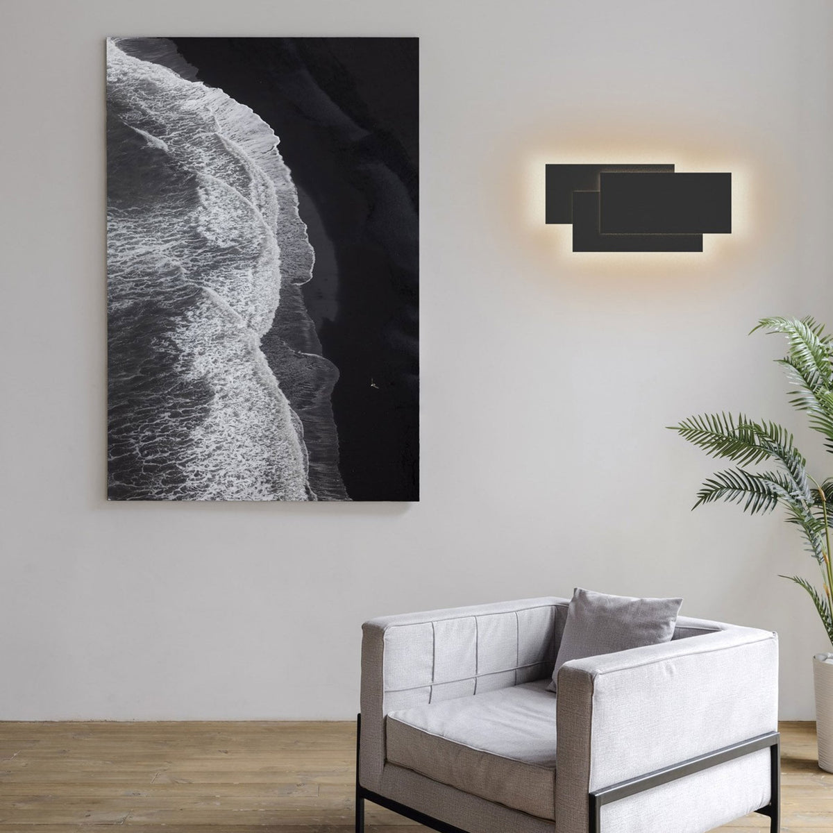 A modern living room with a black wall sconce, abstract art, and a grey armchair.