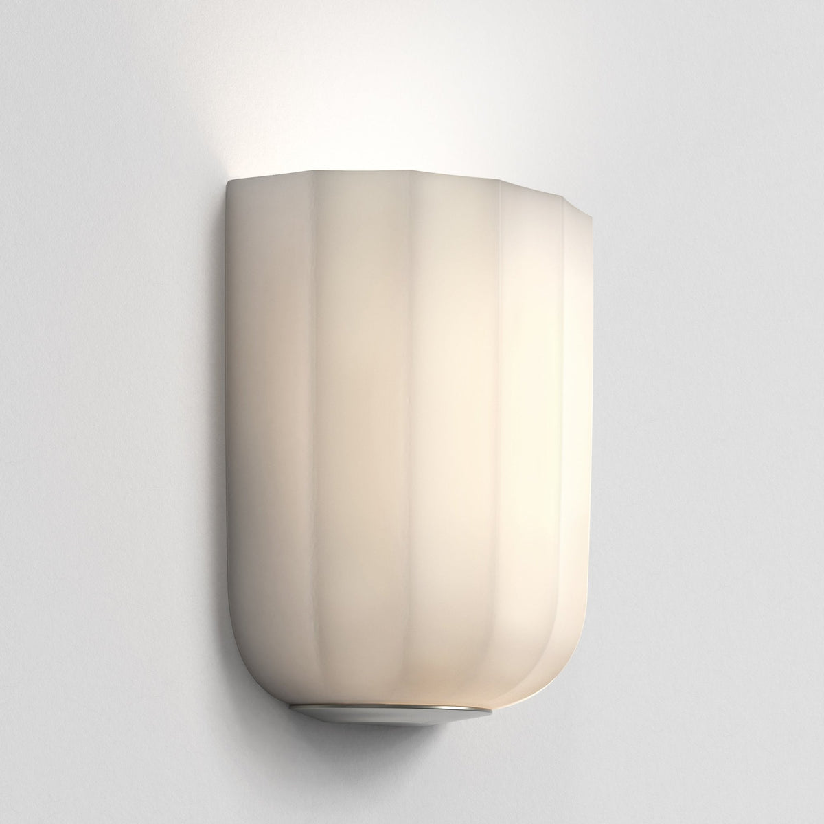 Cream colored wall sconce with vertical ridges and a rounded bottom edge