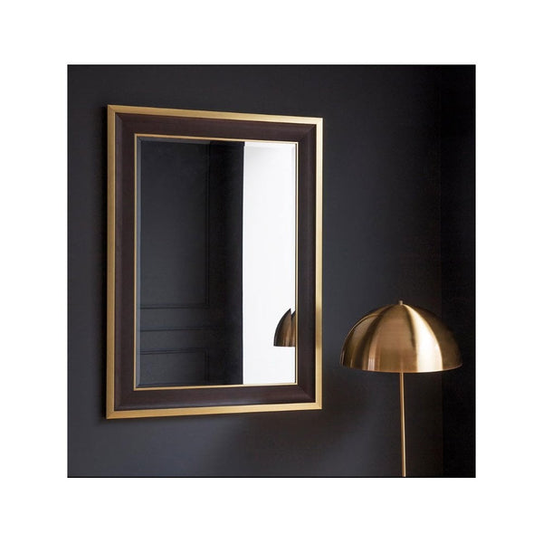 A rectangular mirror with a dark brown and gold frame hangs on a dark wall.