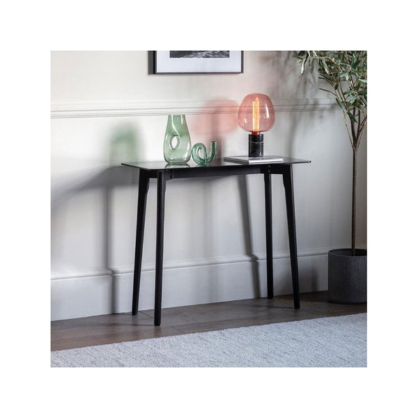 A black console table with a white top, styled with a green vase and an orange lamp.