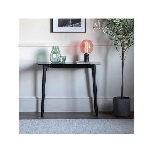 A black console table with a white top, styled with a green vase and an orange lamp.