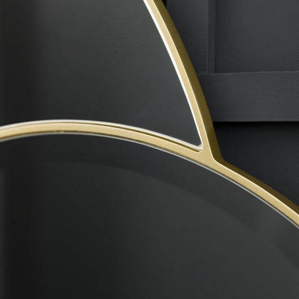 Close-up of the overlapping gold frames of two round mirrors on a dark wall.