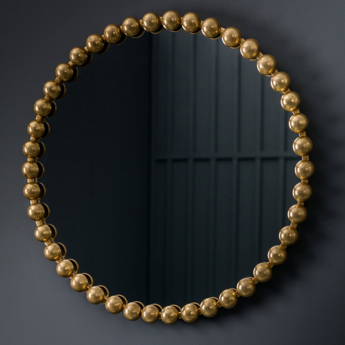 A close-up of a round mirror with a gold beaded frame.