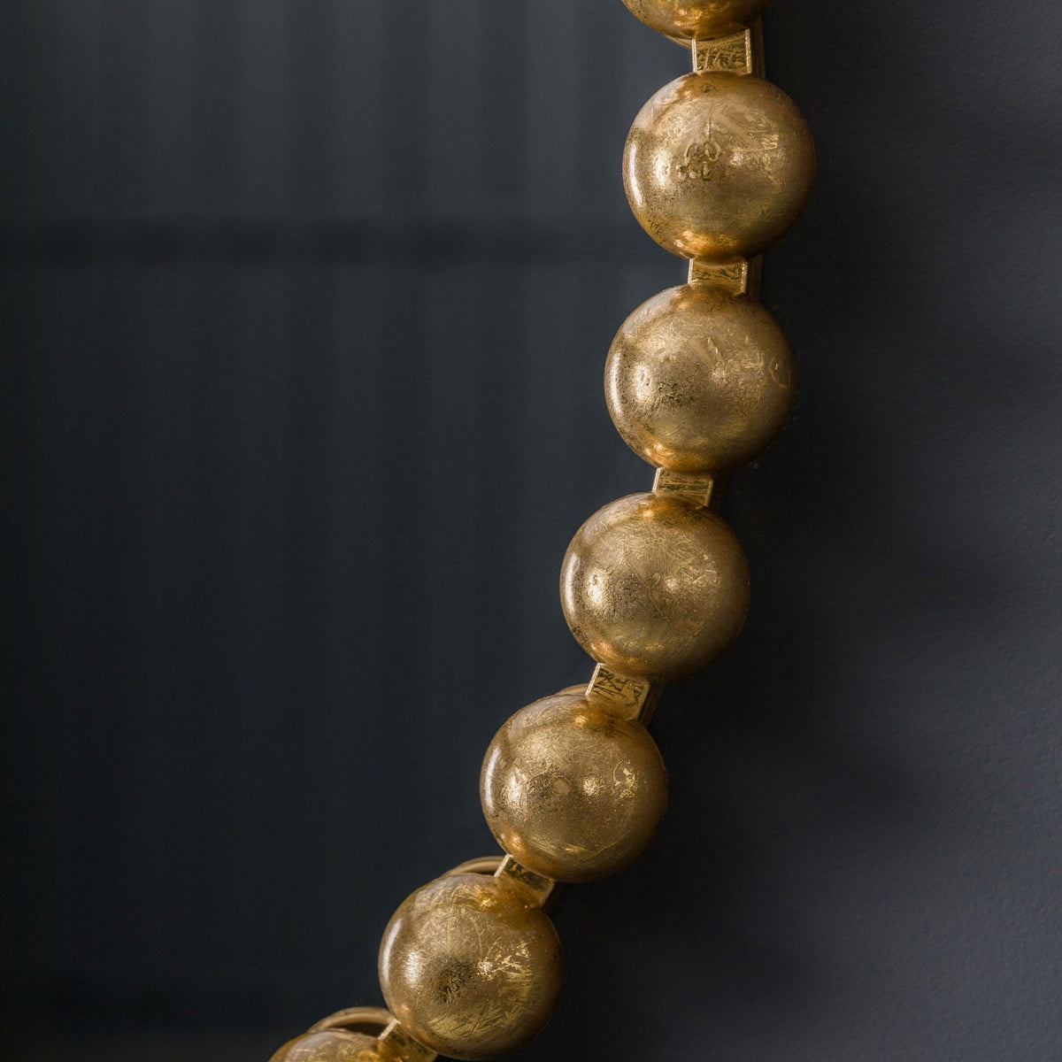 A close-up of the gold beaded frame of a mirror.