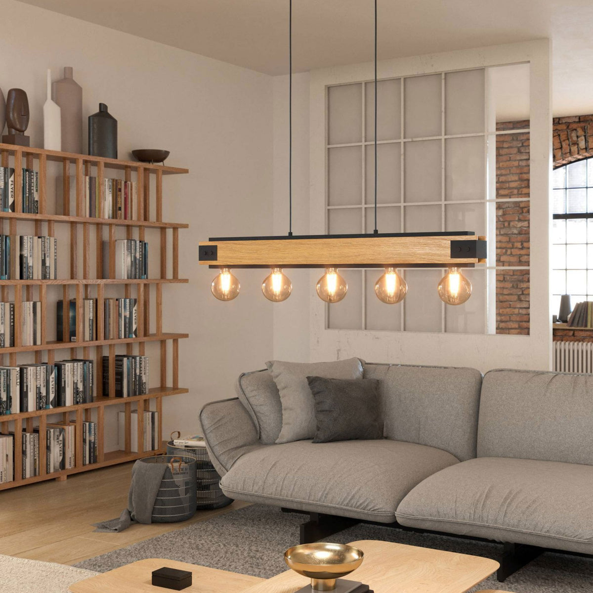 A living room with a long light fixture made of wood and metal, featuring five exposed bulbs.