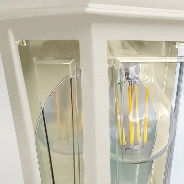 A close-up of the cream outdoor wall light, showing the clear glass panels and filament bulb.