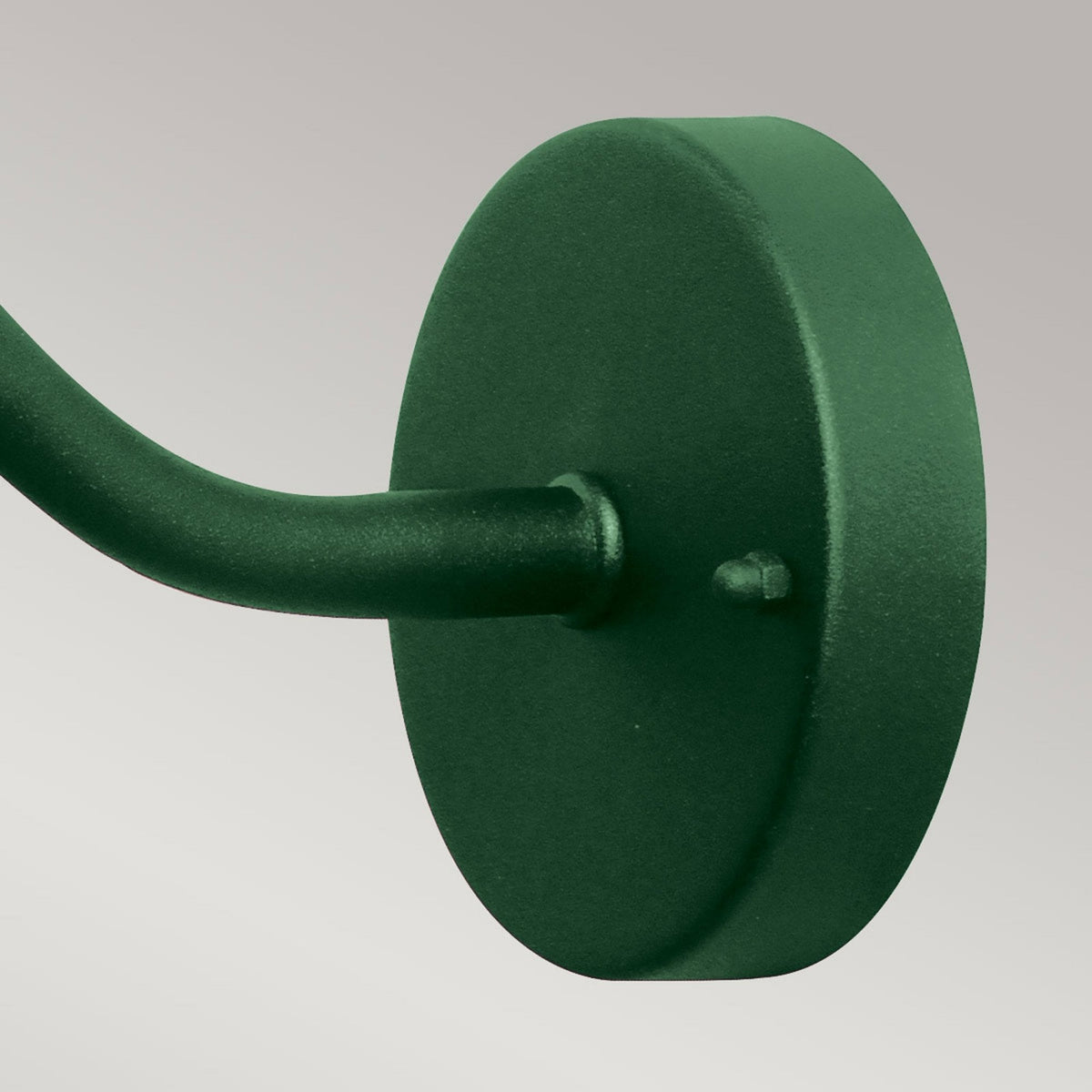 Close-up of the round, dark green wall mount of a barn light fixture.