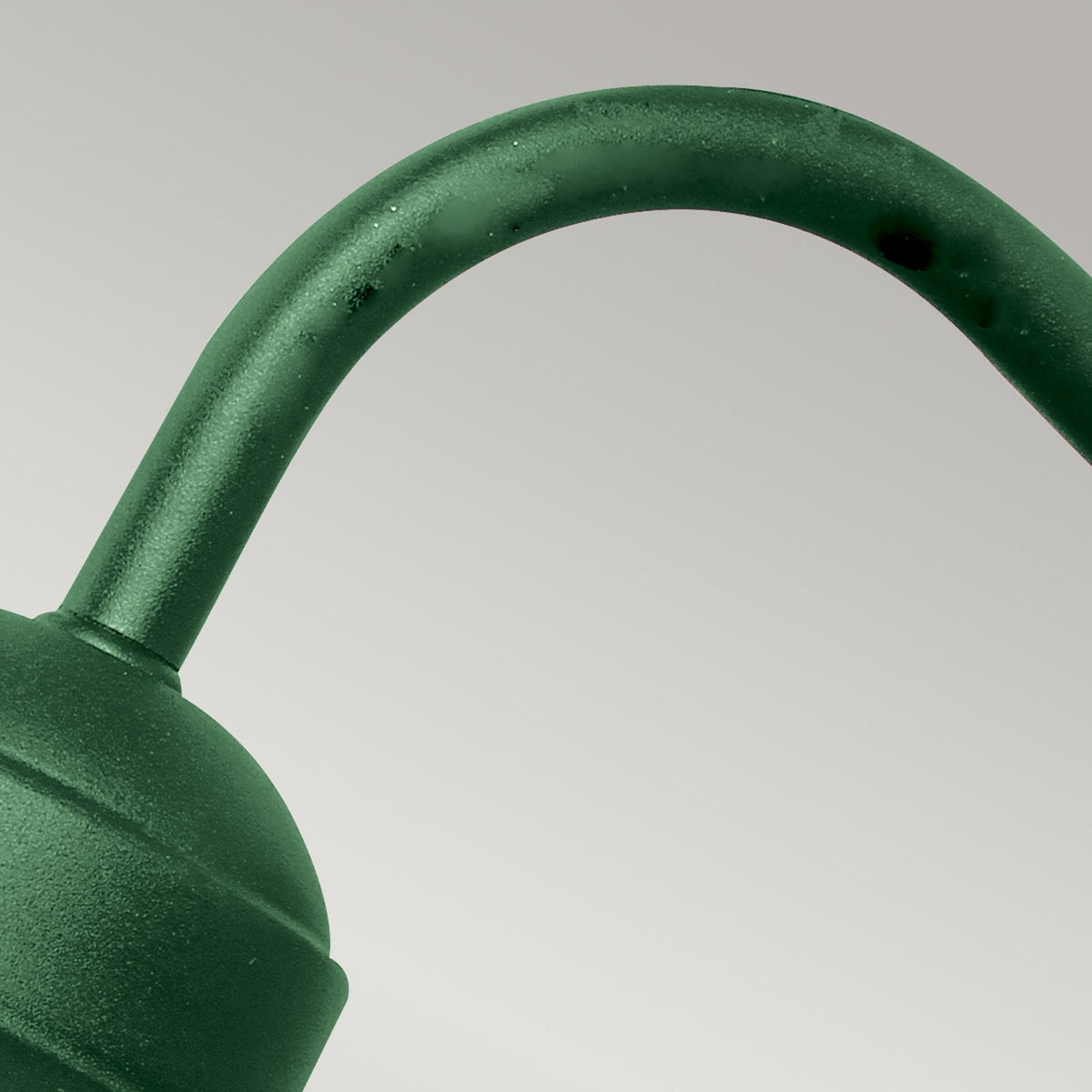 Detailed shot of the curved dark green arm connecting the light to the wall mount.
