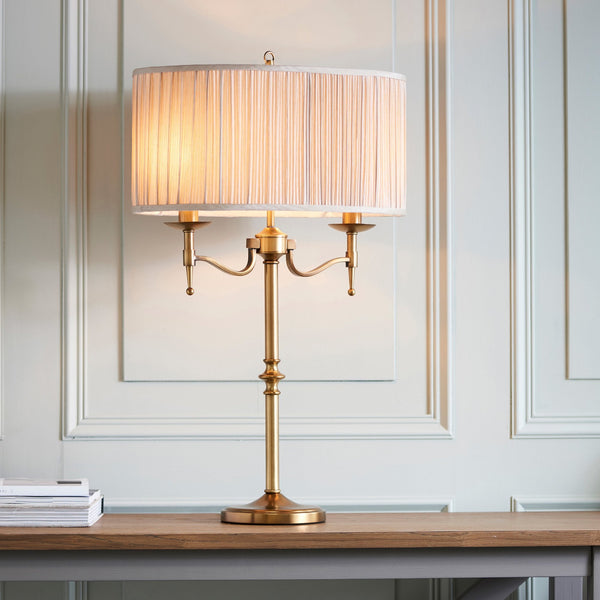A brass table lamp with a pleated shade provides ambient lighting on a wooden desk.
