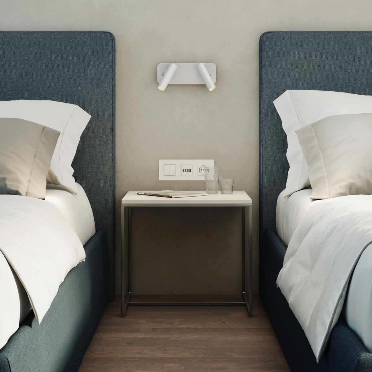 Two beds with blue headboards and white bedding, a nightstand between them with glasses and a magazine