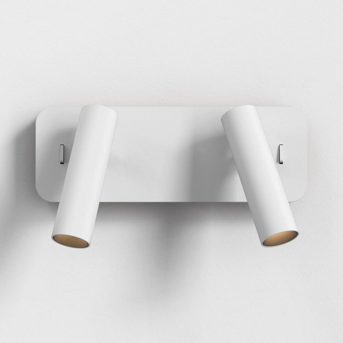 White wall-mounted light fixture with two adjustable cylindrical spotlights