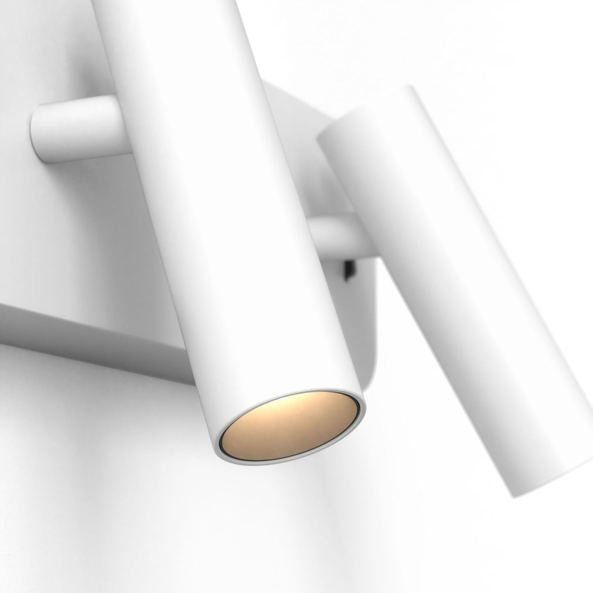 White wall light with two cylindrical heads, one angled down with a warm glow