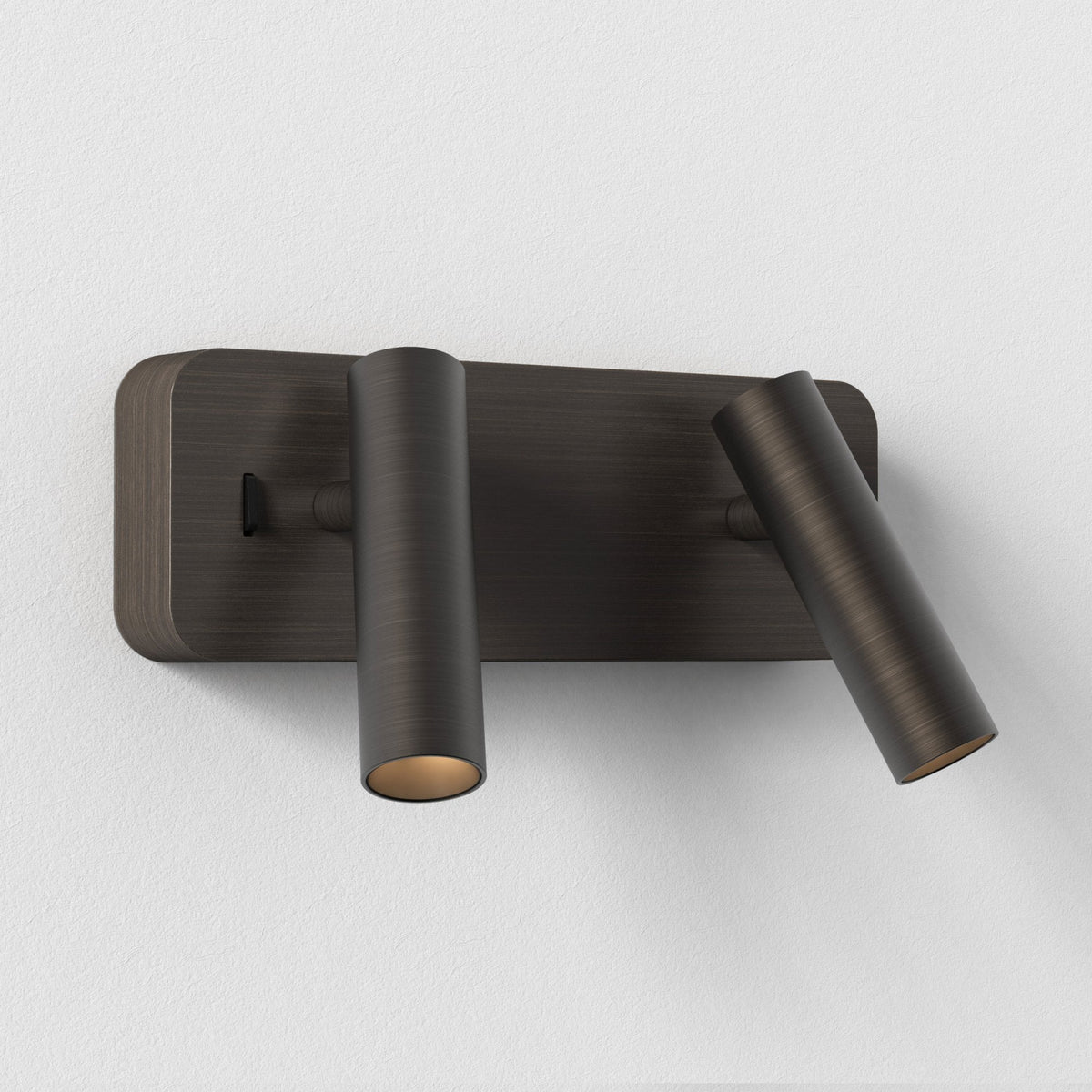 Two cylindrical wall lights in a dark bronze finish, one pointing down, one angled right