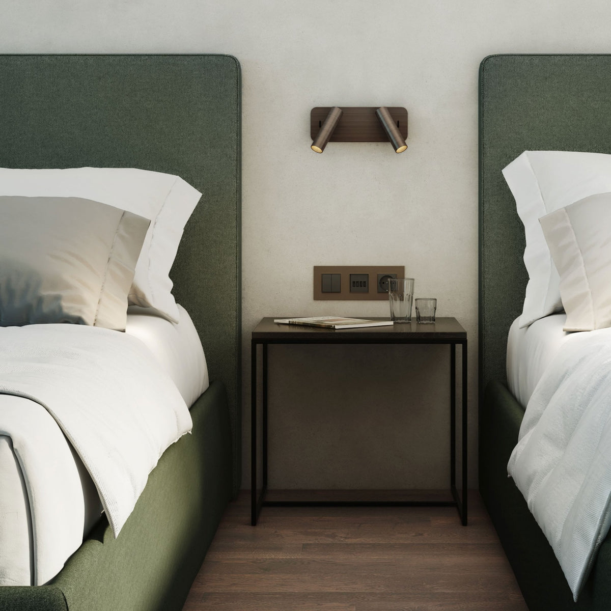Two beds with green headboards and white bedding, separated by a dark brown nightstand with glasses and a magazine