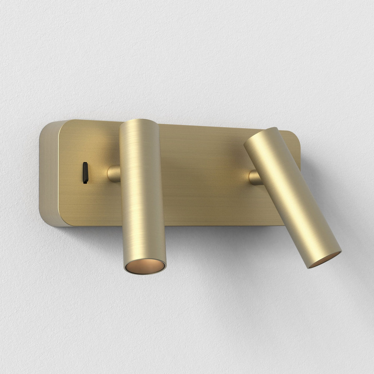 Brushed brass wall light with two adjustable cylindrical heads and a black toggle switch