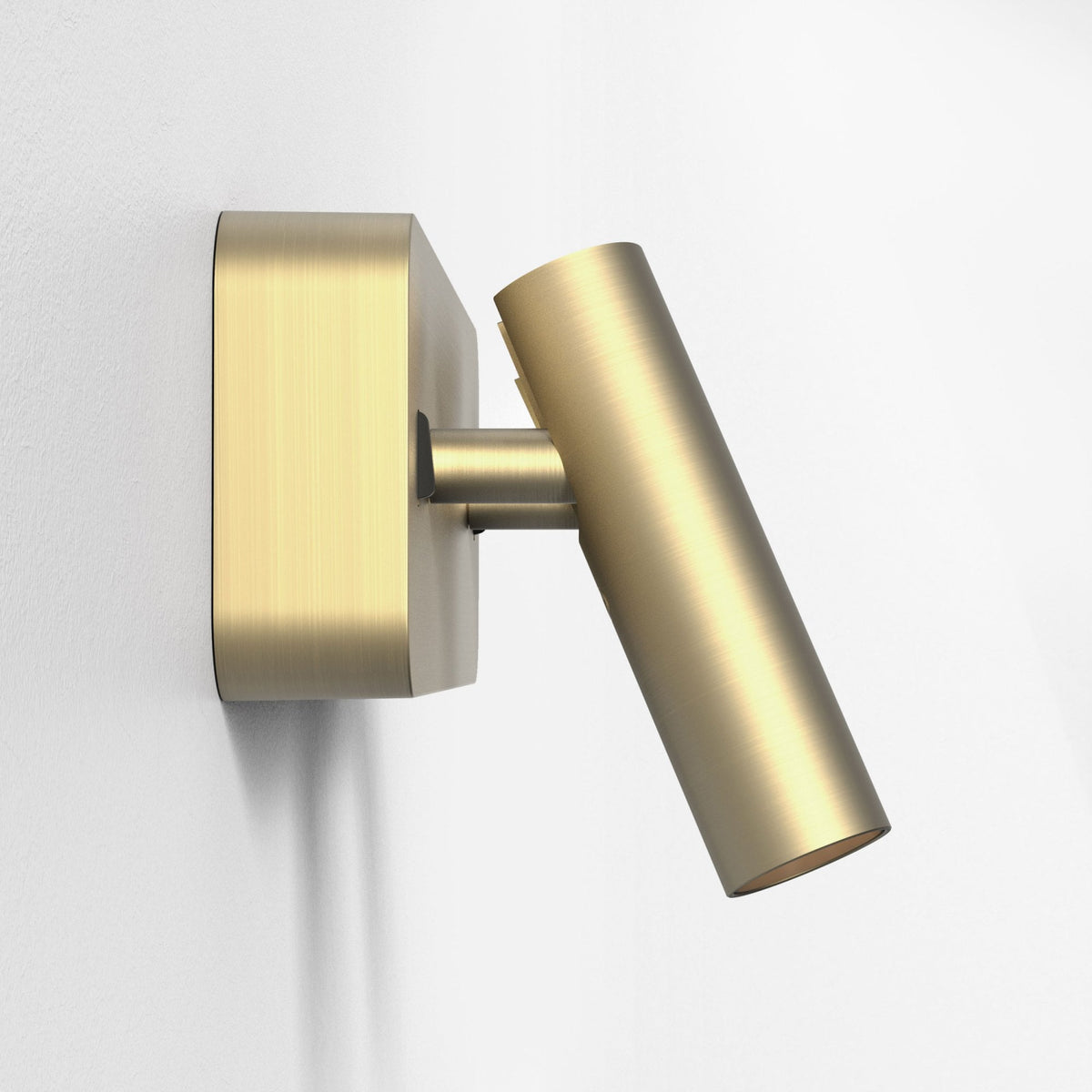 Brushed brass wall-mounted spotlight with a cylindrical head angled downwards