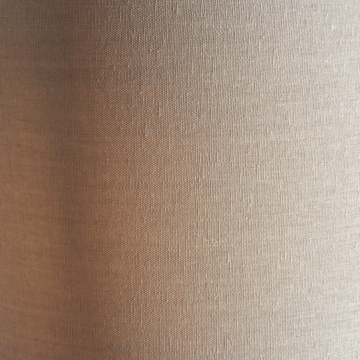 Close-up of the textured fabric of a light beige cylindrical lamp shade.