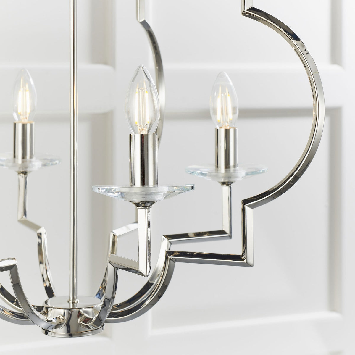 Close-up of the bottom right section of a polished nickel chandelier with a geometric frame and two lights with clear glass accents.