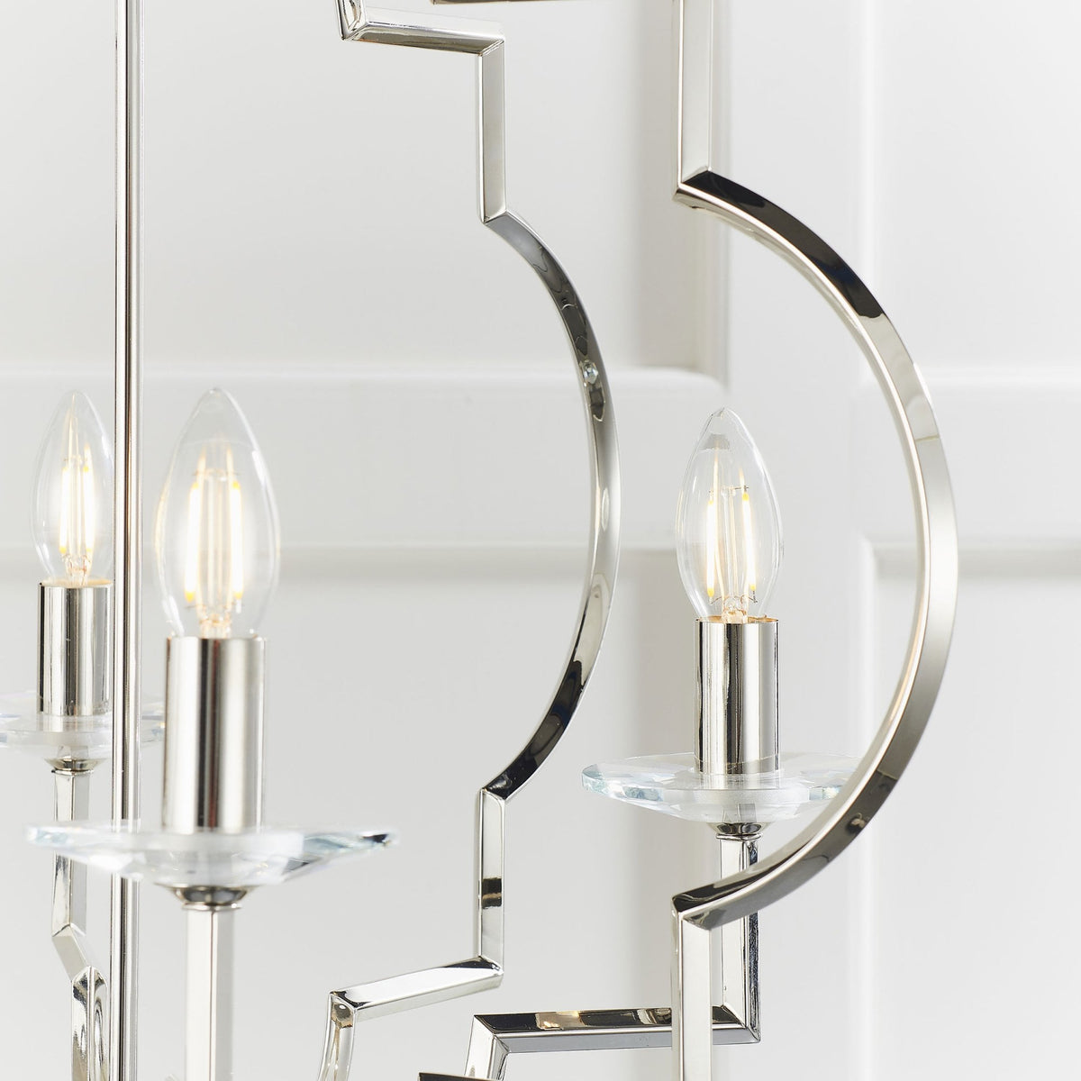 Close-up of the bottom left section of a polished nickel chandelier with a geometric frame and two lights with clear glass accents.
