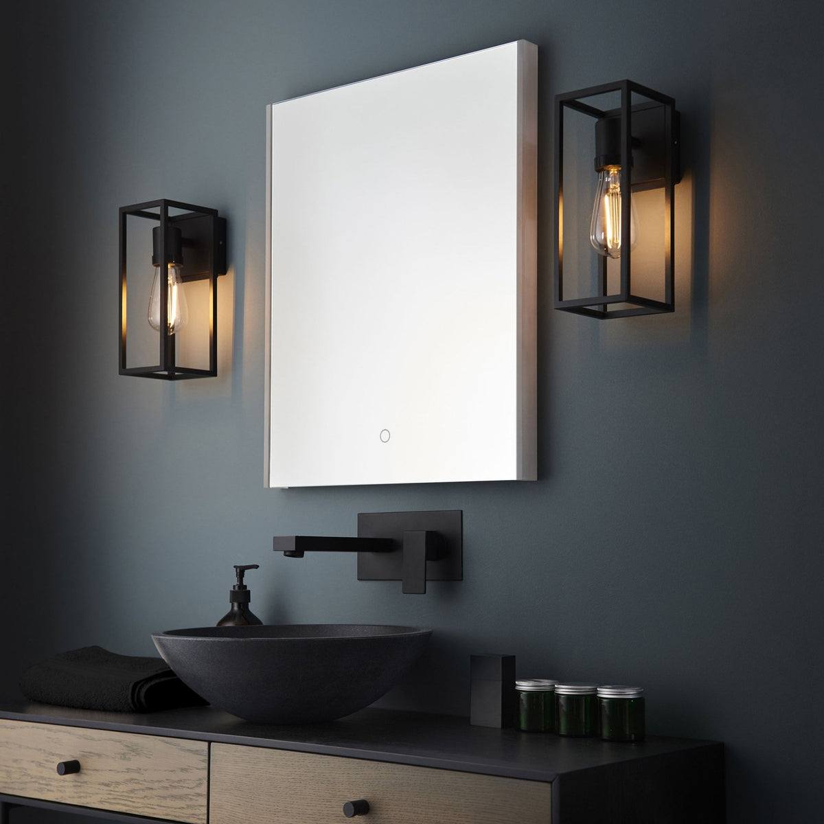 Modern bathroom with a rectangular mirror, black basin, and two black framed wall lights with exposed bulbs.