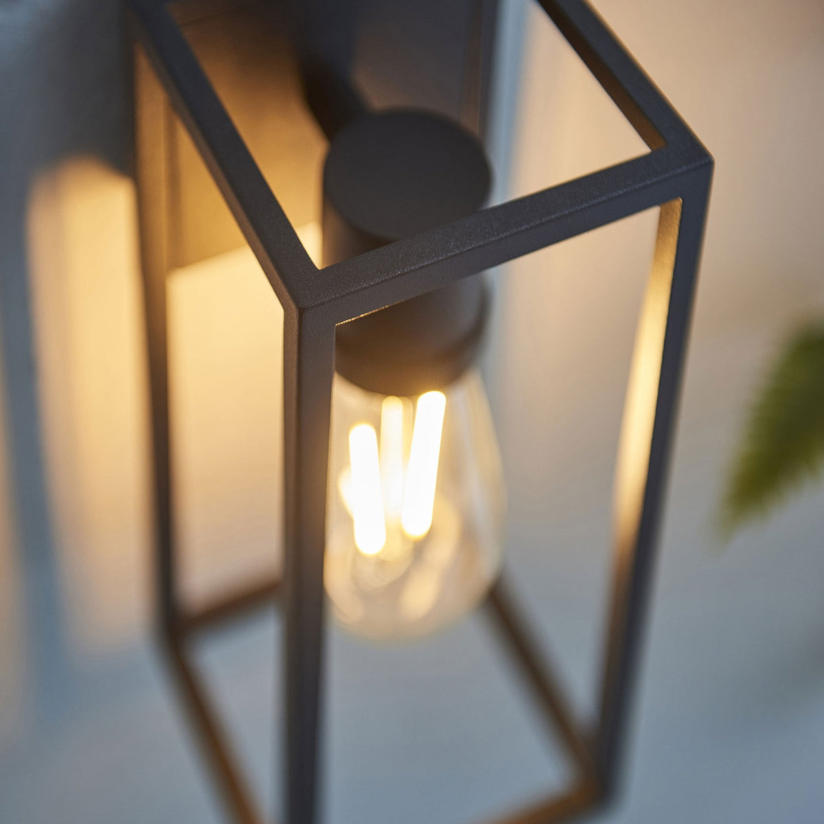 Detailed view of the black frame and illuminated filament bulb of a wall light.