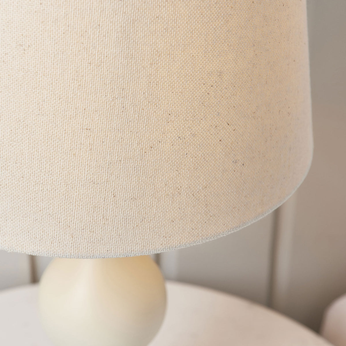 Close-up of the textured linen shade of the cream table lamp.