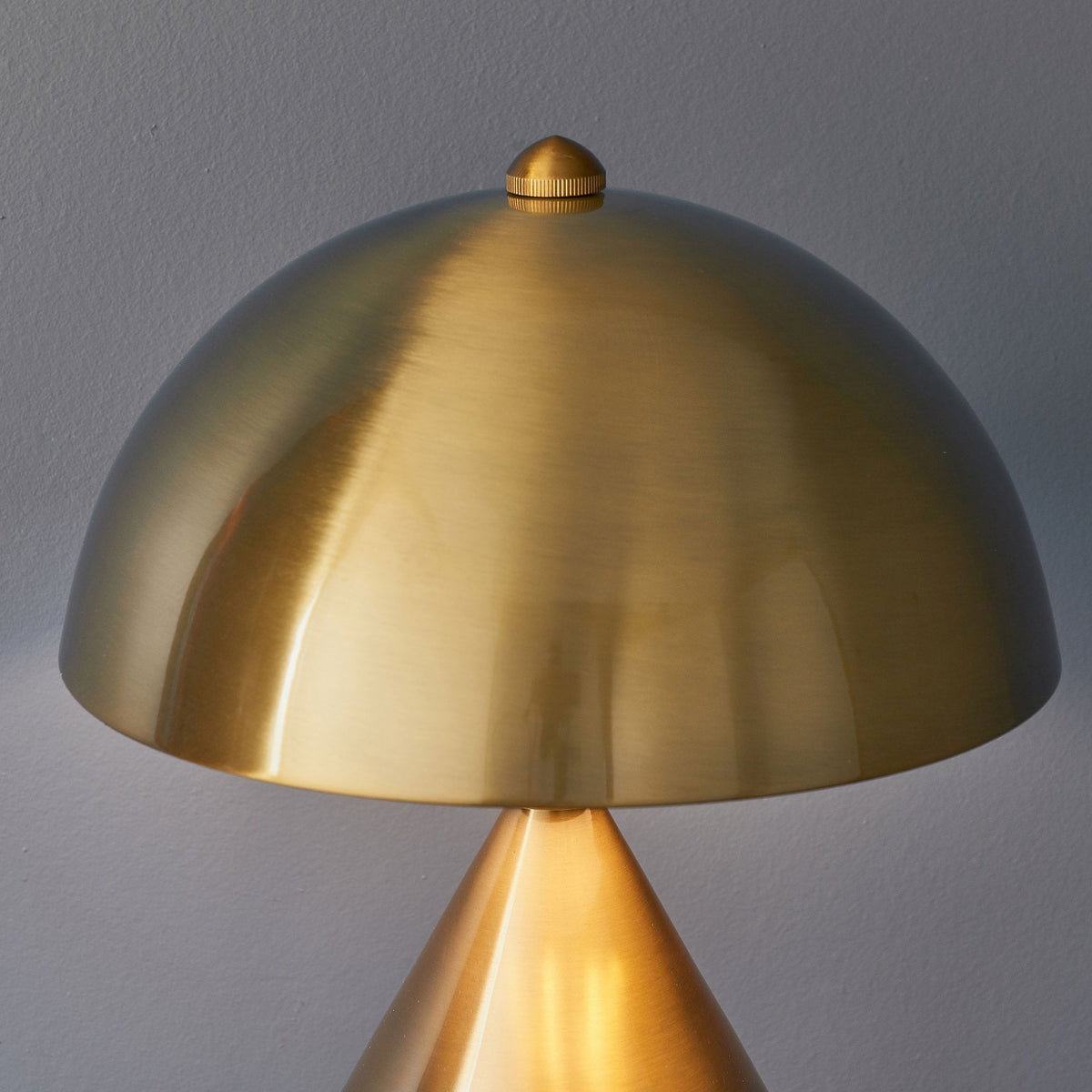 Close-up of the mushroom-shaped shade of a gold table lamp, showing its smooth, reflective surface.