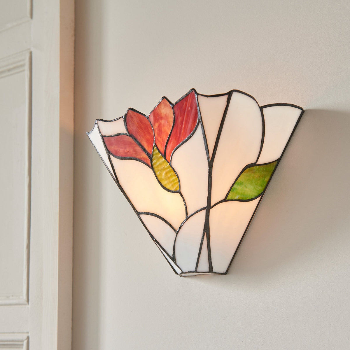 A decorative stained glass wall light featuring a red flower and green leaves.