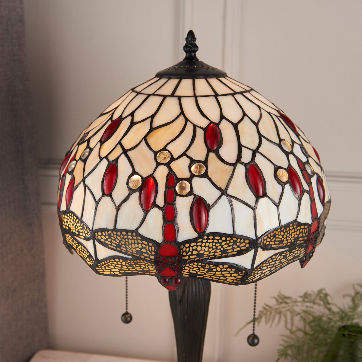 Close-up of the Tiffany lamp shade with red dragonfly design and pull chains.