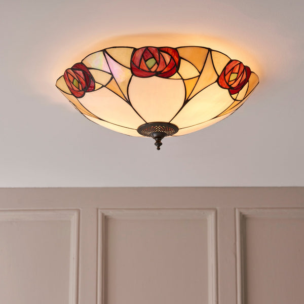 A close-up of a ceiling light featuring a stained-glass rose design, radiating a warm glow.