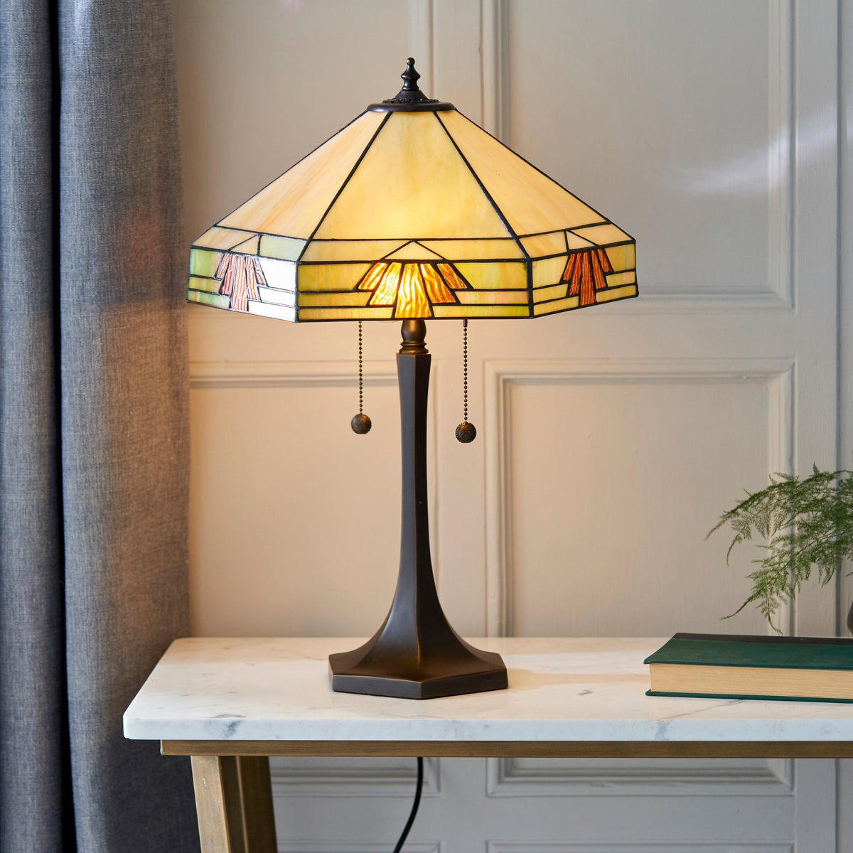 A Tiffany lamp on a marble side table, illuminating a cosy room.