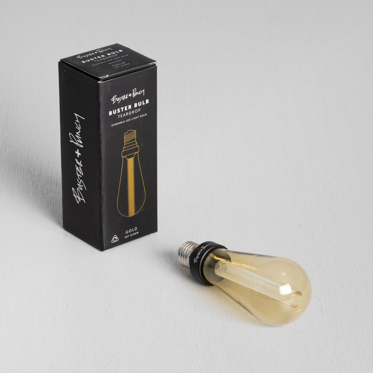 Black box with gold text and a gold teardrop LED light bulb on a white surface. 