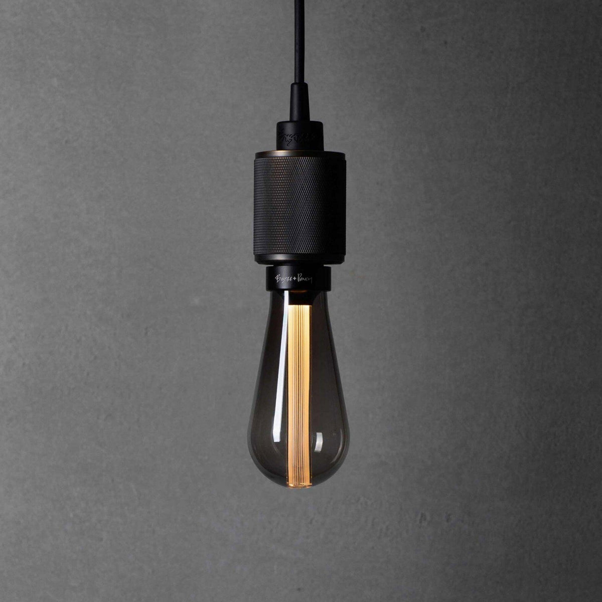 A black pendant light with a textured metal fitting and a clear, elongated bulb with a visible filament.